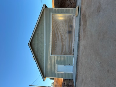Completed detached garage with sage green siding and new concrete apron